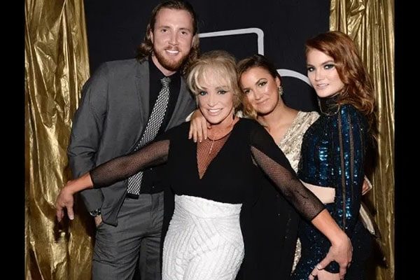 Layla LaCosta Laseter in a shiny blue crop top with her mother in a black top and white pants, her brother in a grey formal dress, and her sister in a white bodycon.